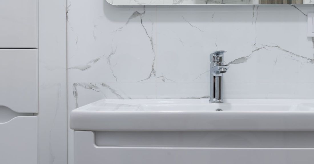 Water Heaters - Modern bathroom interior with white washbasin and tap under mirror reflecting water heater at home