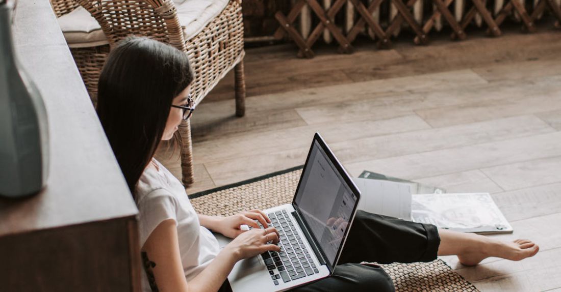 Recycling Program - Young barefoot woman using laptop on floor near books in stylish living room