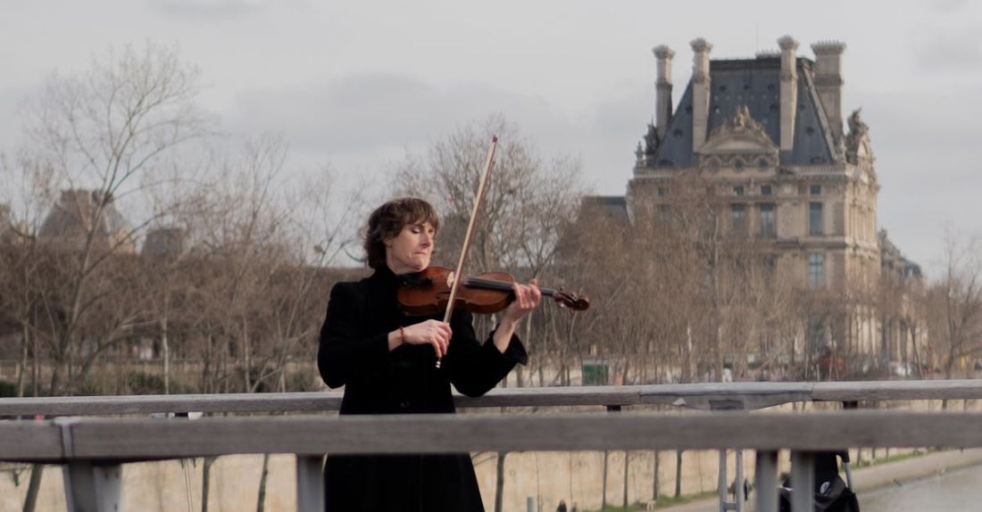 Rooftop Gardens - A woman playing the violin on a bridge